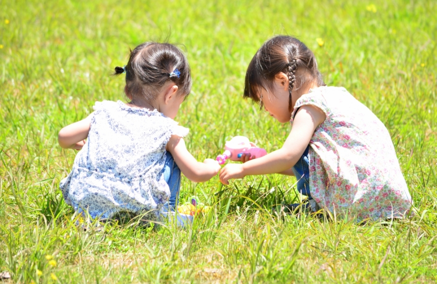 子ども2人が草むら座って遊んでいる様子